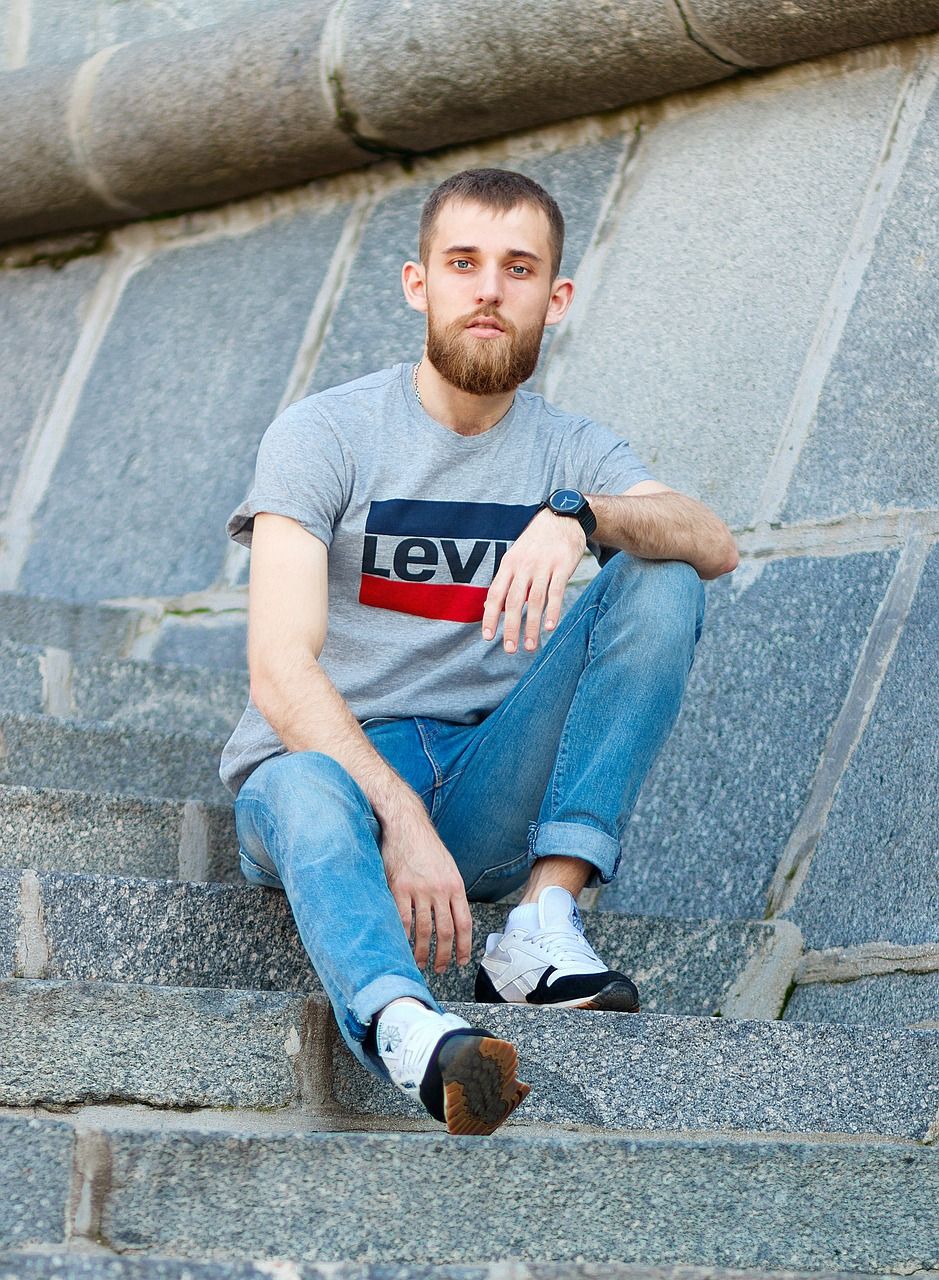 Junger Mann sitzt auf einer Steintreppe